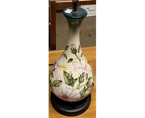 A Moorcroft pottery table lamp decorated with flowers and leaved to a cream ground