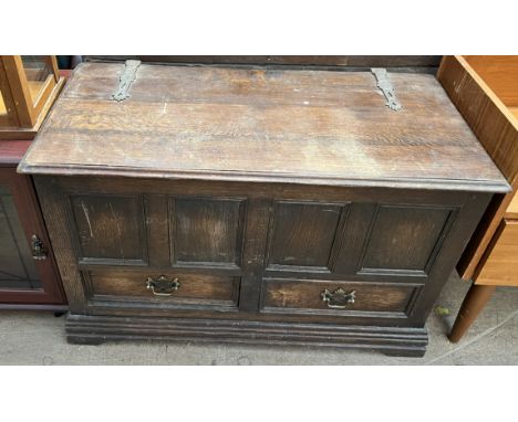 A 20th century oak coffer with a planked top and panelled front with drawers on bracket feet