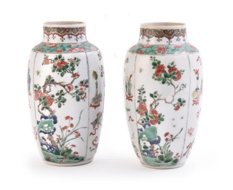 A near pair of Chinese Famille Verte vases, Kangxi, painted with alternating panels of precious objects and flowing prunus, 1