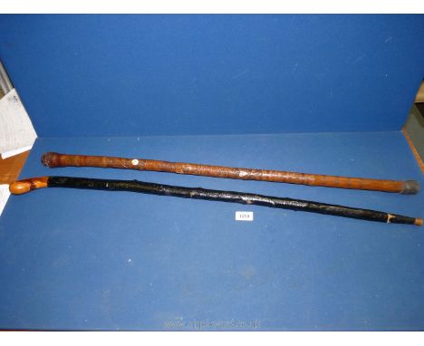 A carved walking stick with bone inserts and another rustic stick.
