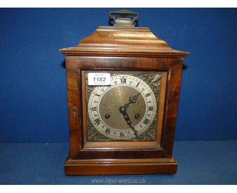 A British Anvil wooden mantle clock with Roman numerals having ornate metal surround to face, carrying handle and pendulum pr