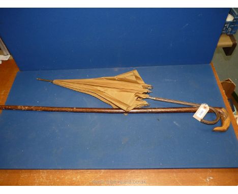 A walking stick and a gold coloured fabric parasol with snake skin handle