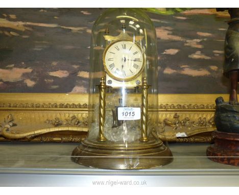A brass anniversary Clock having Roman numerals, under a glass dome and with key and pendulum.