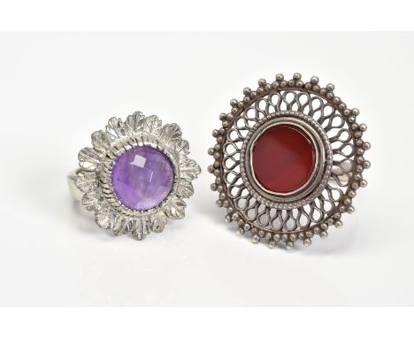 TWO WHITE METAL RINGS, the first of circular design set with a central carnelian panel with an open work metal surround, ring