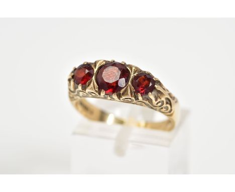 A 9CT GOLD BOAT RING, set with three graduated circular garnets within a scrolling detail gallery, with a 9ct hallmark for Lo