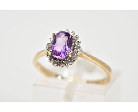 A 9CT GOLD CLUSTER RING, designed with a central oval cut amethyst and single cut diamond surround, to the tapered shoulders,