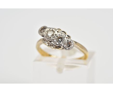 AN EARLY 20TH CENTURY FOUR STONE DIAMOND RING, of cross over scallop design set with an asymmetrical row of two brilliant cut