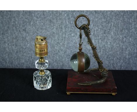 A glass ball  suspended by an anchor. The glass ball would once have held a clock. Not present. Also, a glass desk lighter.  