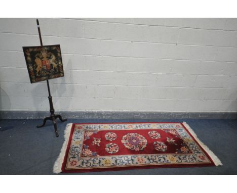 A 20TH CENTURY MAHOGANY NEEDLEWORK FIRESCREEN, screen has adjustable height, on splayed legs, height 150cm, along with a red 
