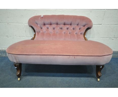 A VICTORIAN SOFA, with a shaped button back, and covered in pink upholstery, on shaped front legs, and ceramic casters, lengt