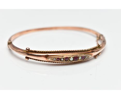 A YELLOW METAL RUBY AND SPLIT PEARL HINGED BANGLE, the marquise panel set with alternating circular cut ruby and split pearls