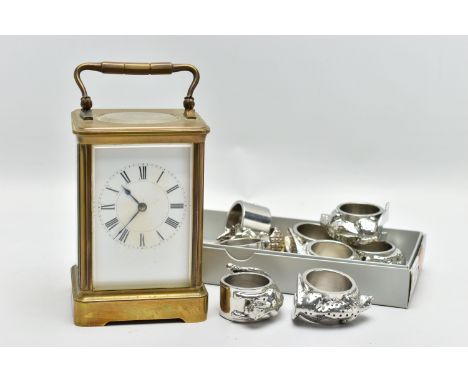 A BRASS CARRIAGE CLOCK AND NAPKIN RINGS, brass carriage clock with glass viewing panels, unsigned white dial, Roman numerals,