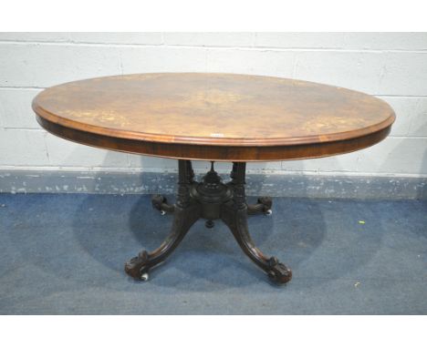 A LATE VICTORIAN WALNUT OVAL TILT TOP LOO TABLE, with marquetry inlay, turned supports, fluted acanthus carved legs, on ceram