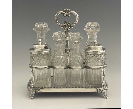 A George III Regency silver and cut glass eight bottle cruet, the stand with rounded rectangular base with gadroon border ato