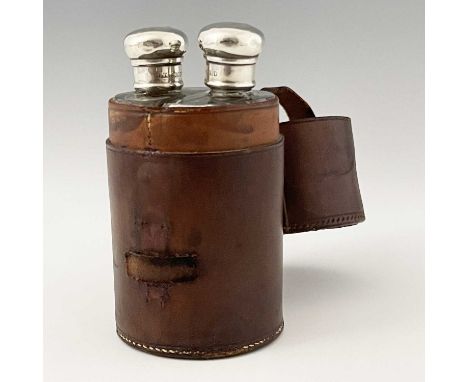 An Edwardian travelling leather cased flask set, each glass bottle of hemispherical form with hallmarked silver cap secured b