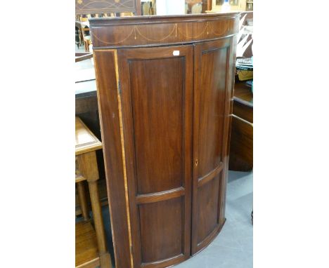 A NINETEENTH CENTURY PANELLED MAHOGANY BOW FRONT CORNER CUPBOARD 