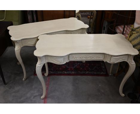 A pair of continental cream painted three drawer console tables with carved floral and foliate decoration and cabriole suppor
