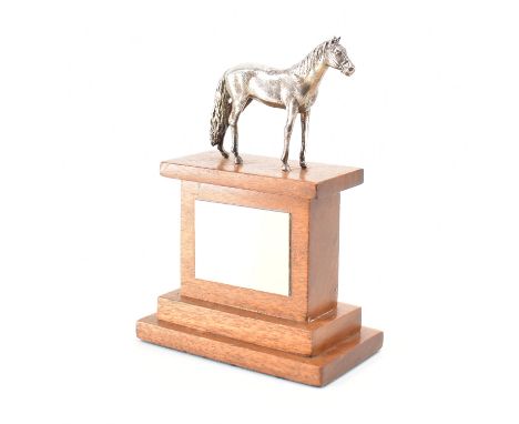 A hallmarked silver horse trophy. The trophy having a standing silver horse to the top on a wooden stepped plinth base &amp; 