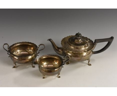 An Edwardian silver three piece bachelor's tea service, comprising teapot, milk jug and sugar basin, wavy borders, scroll han