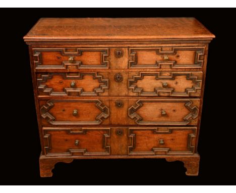 An 18th century oak block front chest, moulded top above four long graduated drawers applied with geometric mouldings, bracke