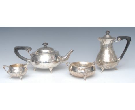 An Arts and Crafts silver four piece tea and coffee service, comprising teapot, coffee pot, sucrier and milk, each planished 