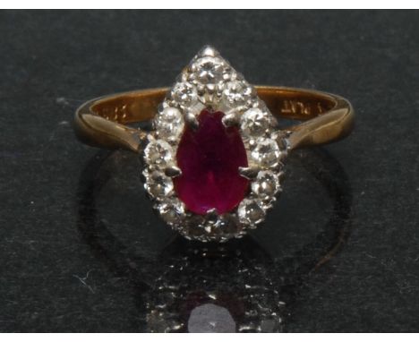 A ruby and diamond pear drop cluster ring, central pear drop red ruby approx 0.35ct, surrounded by a band of thirteen round b