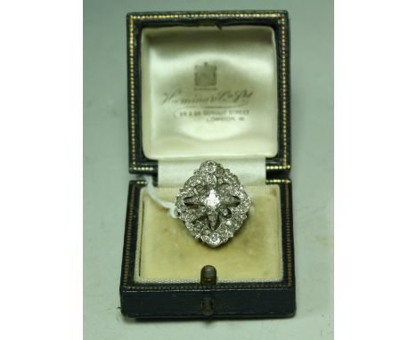 An Art Deco diamond star cluster ring, central cushion cut diamond approx 0.30ct with multi layer eight point star crest ador