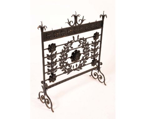 A large Arts and Crafts wrought iron country house firescreen, scroll finials above a deep frieze applied with a row of rose 