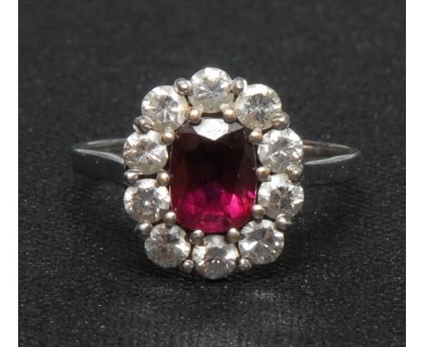 An 18ct white gold ruby and diamond cluster ring, the central faceted ruby of good colour, claw set within ten brilliant cut 