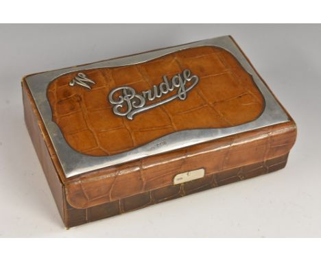 An Edwardian silver mounted crocodile skin bridge box, hinged cover applied with script and enclosing twin playing card compa