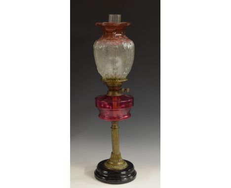 An early 20th century brass and cranberry glass table oil lamp, moulded frosted shade, Eltex burner, fluted column, circular 