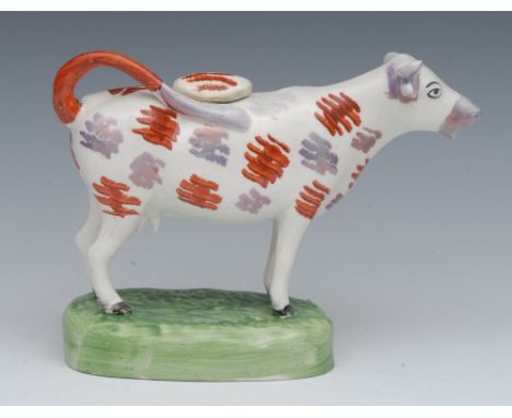 A 19th century Swansea cow creamer, standing four square, iron red, and lustre patch markings, oval green base, 14cm high, c.