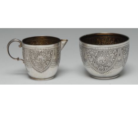 A Victorian silver cream jug and sugar basin, each chased with dense scrolling foliage, gilt interiors, the bowl 8cm diam, Fr