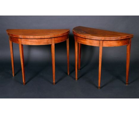 A pair of George III mahogany demi-lune card tables, each with folding crossbanded top enclosing a baize lined playing surfac