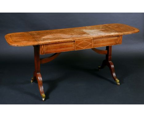 A Regency satinwood crossbanded mahogany sofa table, rounded rectangular top with fall leaves above a long frieze drawer inla