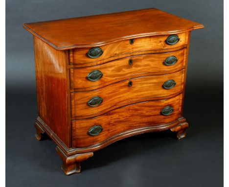 An American mahogany serpentine fronted chest, moulded oversailing top above four long graduated cockbeaded drawers, oval bra