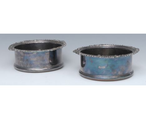 A pair of early 20th century silver plated wine coasters, draught turned bases, gadrooned leafy scrolls border, 17cm diam; a 