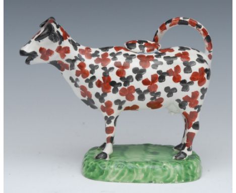 A North of England cow creamer, standing four square, with black and rust stylised leaf  patch markings, rounded rectangular 