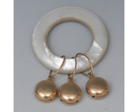 An early 20th century mother-of-pearl and gold coloured metal teething ring, the ring quite plain, suspended with three bun s