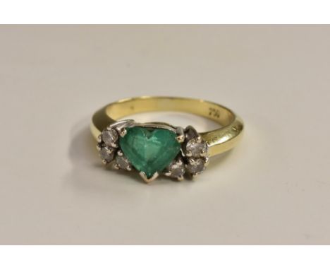 An emerald and diamond cluster ring, central heart shaped light green emerald approx 0,80ct, flanked either side by a trio of