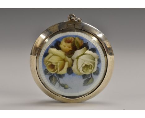 An early 20th century silver and enamel circular rouge box, hinged cover decorated with roses on a pale blue ground, verso en