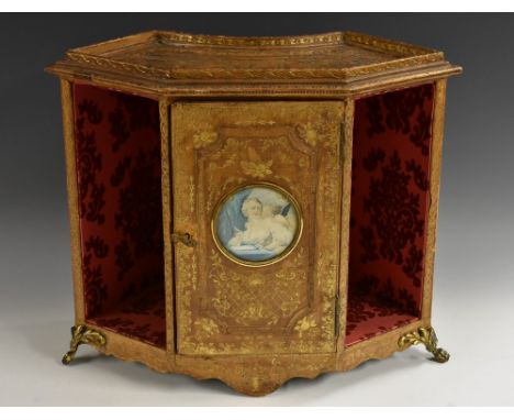 An Italian gilt metal mounted tooled leather table cabinet, the fan shaped top with shallow gallery above a rectangular door 