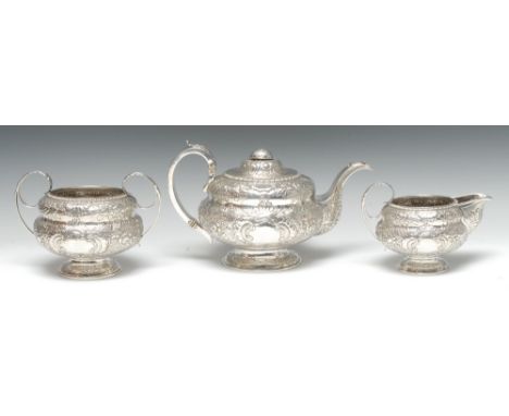 A George IV Irish silver three piece compressed ogee tea service, comprising teapot, milk jug and sugar basin, profusely chas