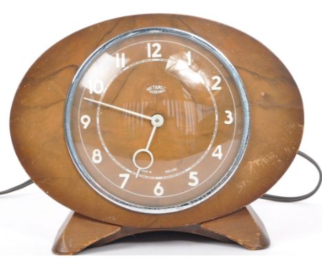 An original 1950's retro vintage electric free standing clock of oval form having an oak wood face&nbsp;with curved glass cov