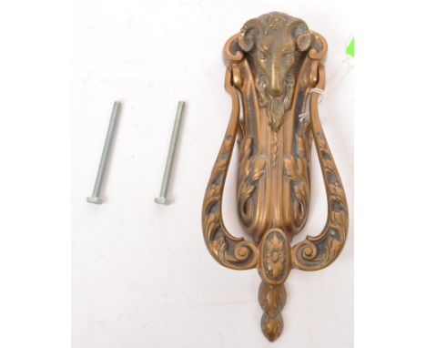 A large brass door knocker decorated with a rams head with two screw fixings to verso. Measures approx. 24cm long