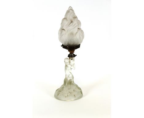 An Art Deco figural table lamp, in the form of a naked maiden seated on rocks holding a flambe shade aloft, 43cm high