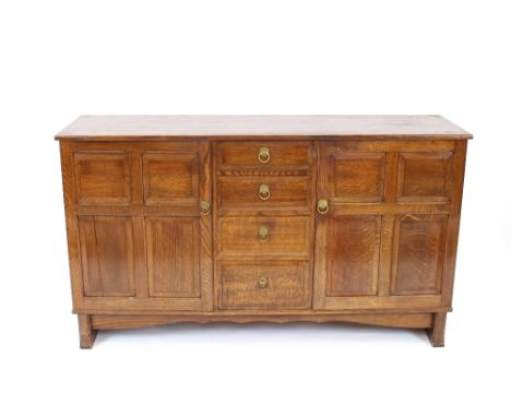 A Heal's design oak sideboard, fitted four central drawers flanked by deep cupboards, enclosed by quarter panel fielded doors