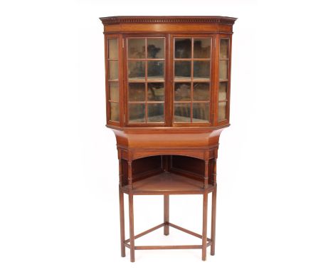 An early 20th Century Liberty & Co., mahogany corner cabinet, the upper section enclosed by glazed panels, raised on turned c