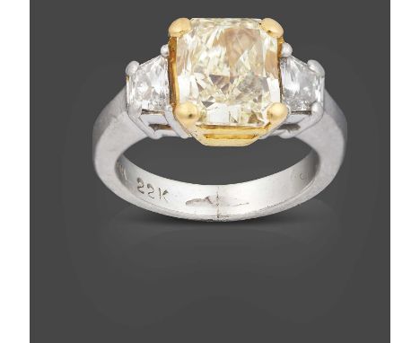 the radiant cut fancy light yellow diamond in yellow claw settings, flanked by trapezium cut diamonds in white claw settings,