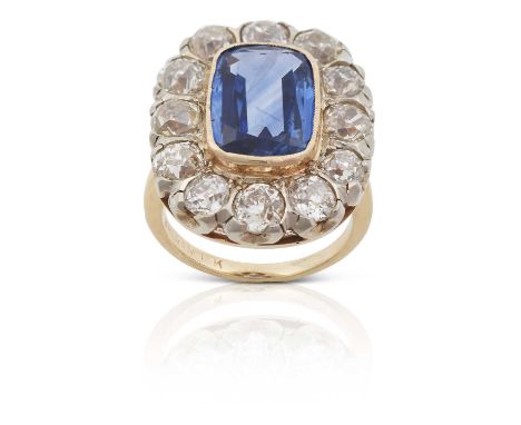 the rectangular cushion shaped sapphire in a yellow millegrain setting, within a border of old cut diamonds in white claw set